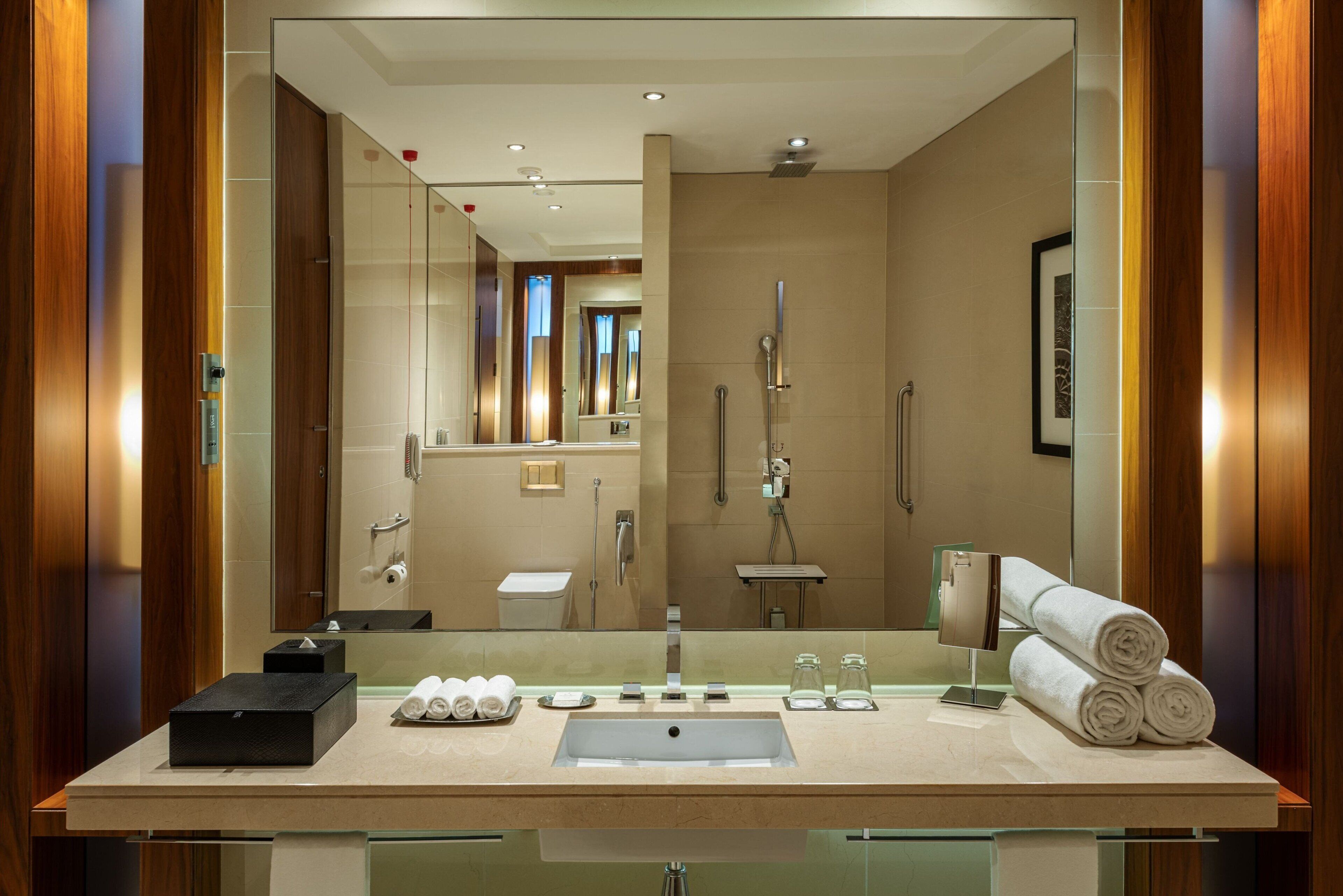 A modern bathroom with a large mirror, a sink, and a shower area.