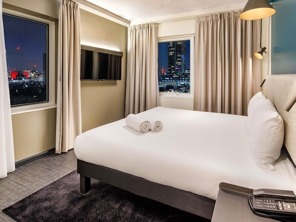 A hotel room with a bed, a TV, a city view, and a telephone. - ibis London Blackfriars (London)