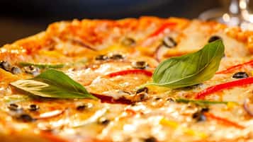 Una pizza con diferentes ingredientes y hojas de albahaca por encima.
