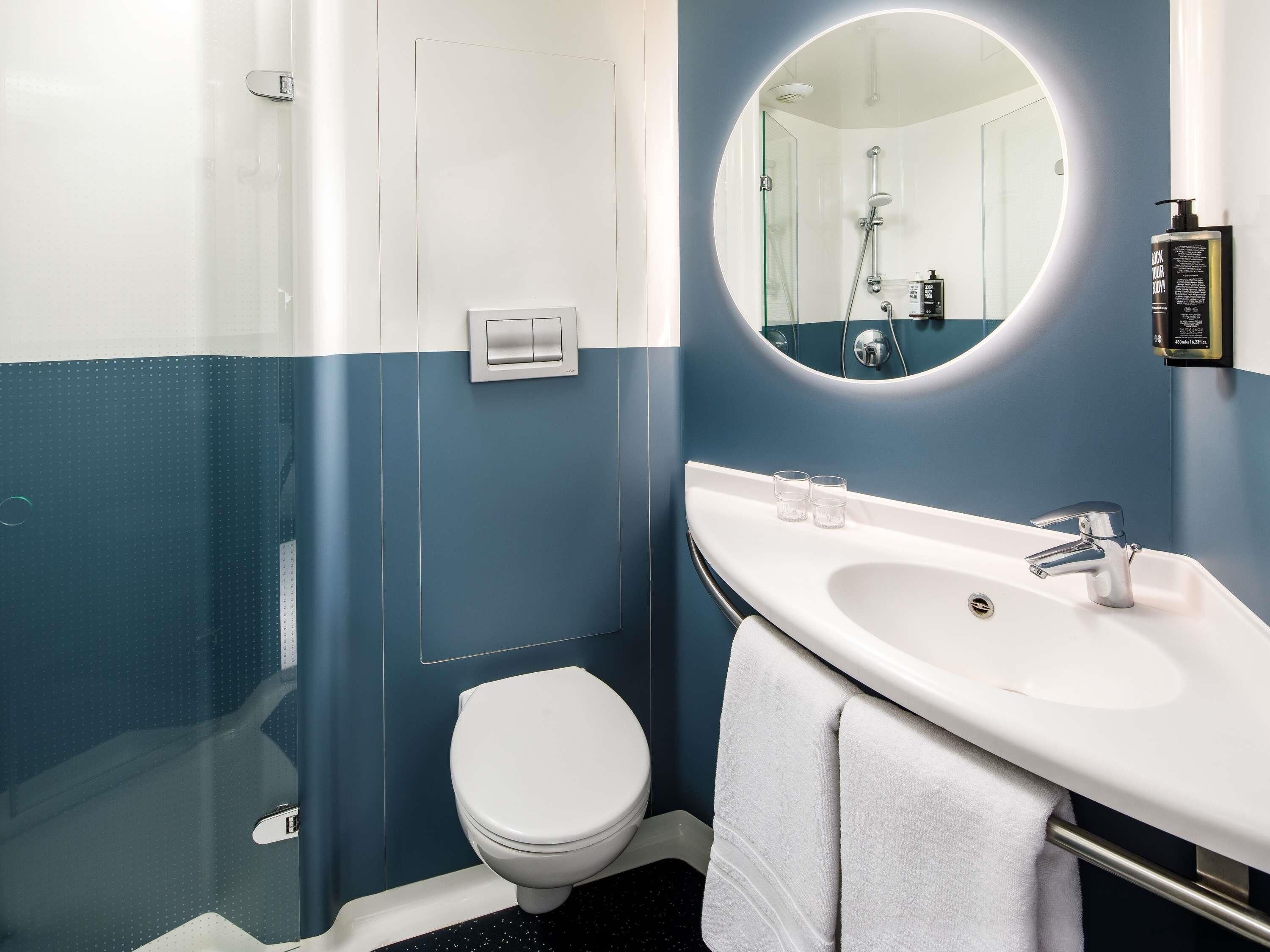 Een badkamer met een wit toilet, een wastafel met spiegel en een douche.