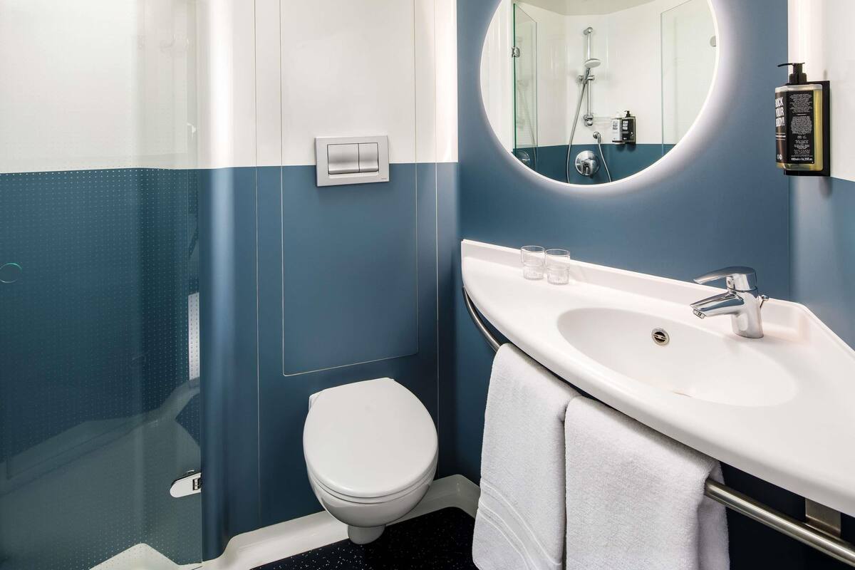 A bathroom with a white toilet, a sink with a mirror, and a shower area.
