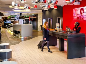 Un hall d’hôtel moderne comprenant un comptoir d’accueil, un espace salon et un bar.