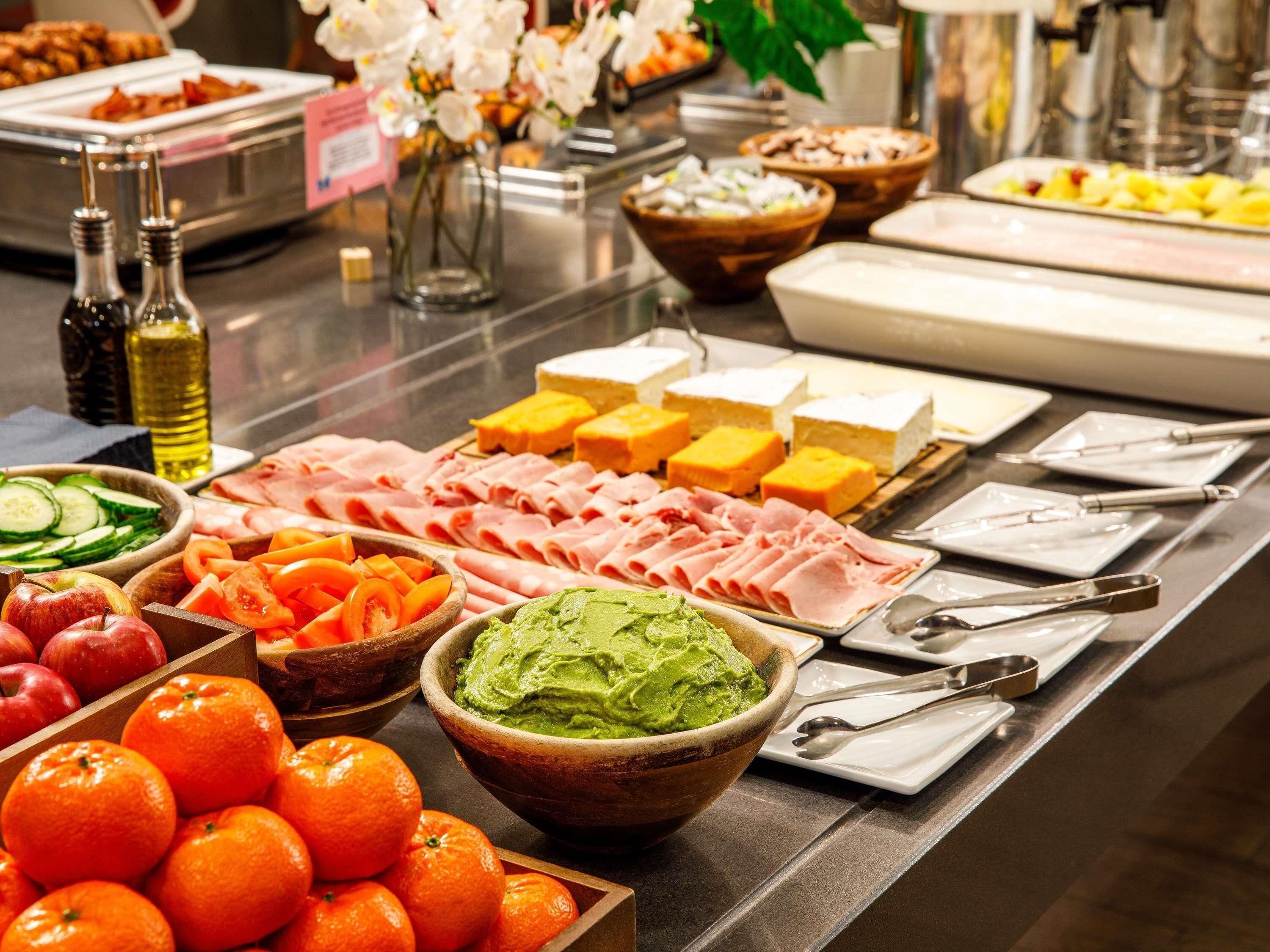 A buffet with various food items including meats, cheeses, and fruits.