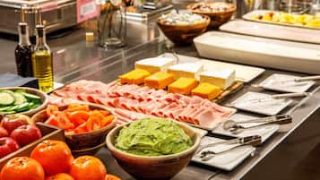 A buffet with various food items including meats, cheeses, and fruits.