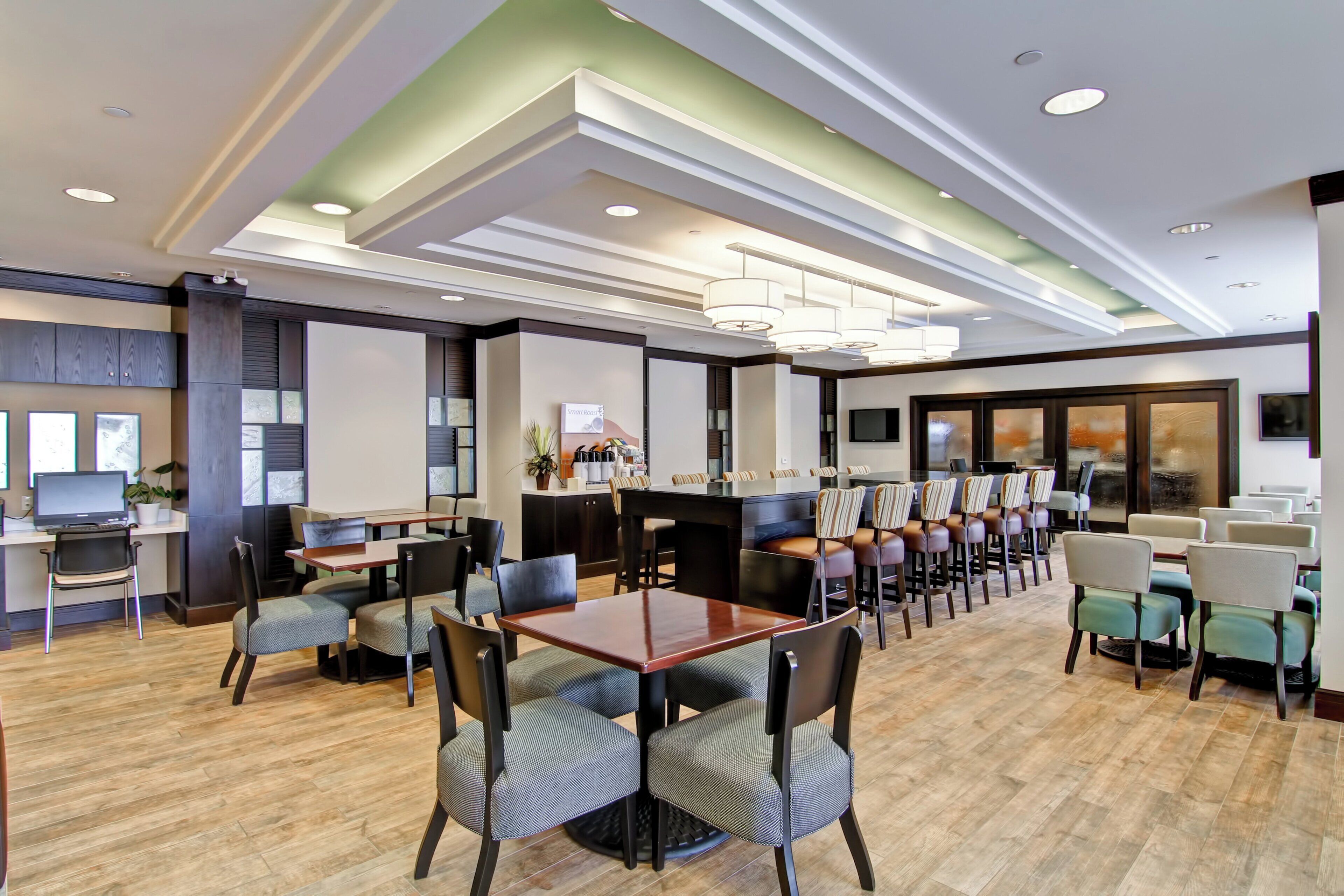 A hotel lobby with a dining area, multiple tables, and chairs.