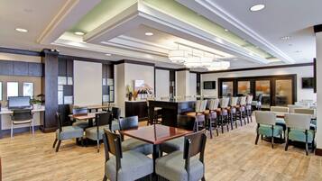 A hotel lobby with a dining area, multiple tables, and chairs.