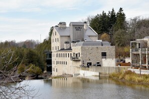 A stone building with a sign reading 'ELORA MILL' near a body of water. - Holiday Inn Express Hotel & Suites Waterloo - St Jacobs by IHG (Township of Woolwich)