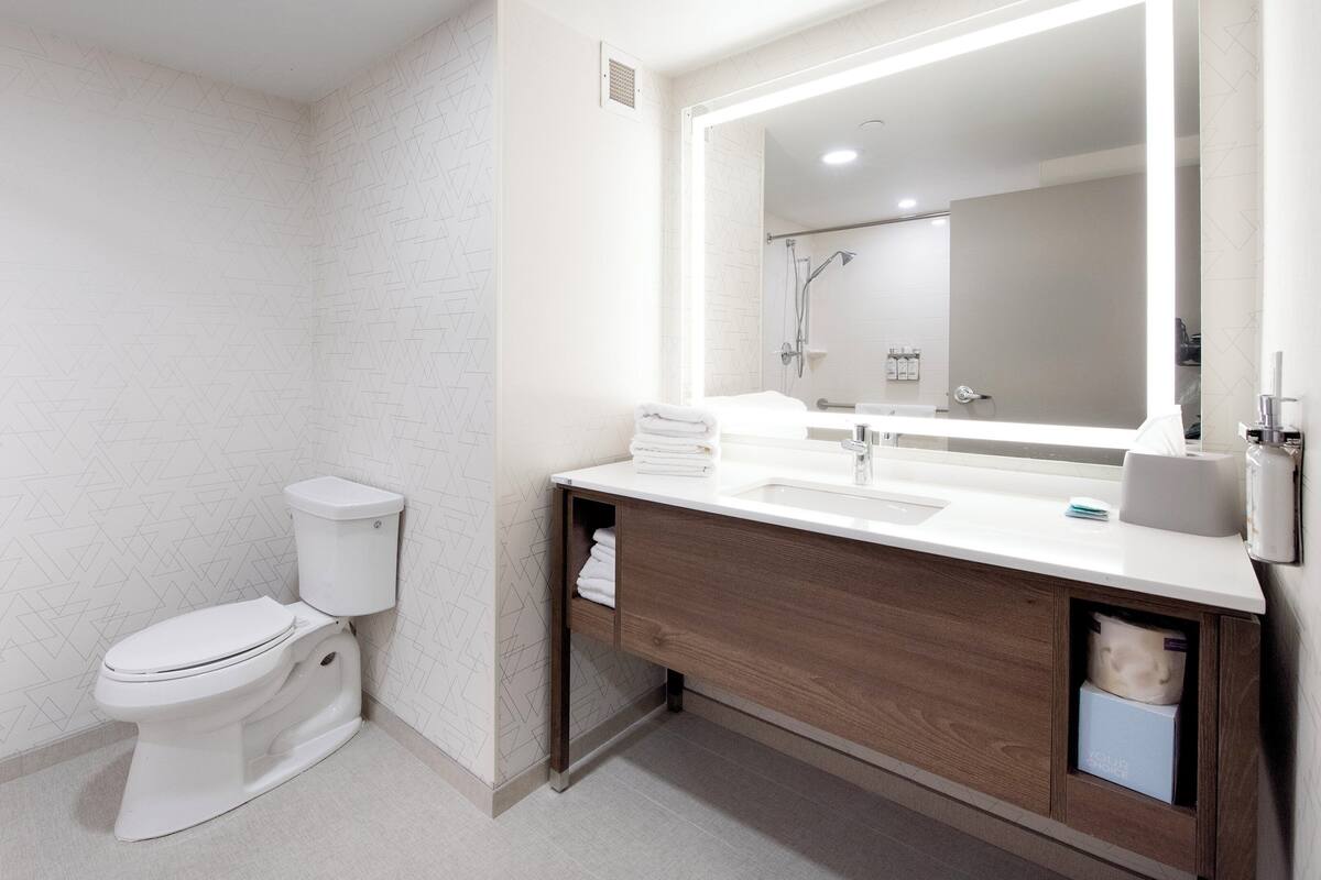 A modern bathroom with a toilet, sink, and shower.