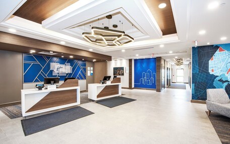 A modern reception area with two reception desks, a map mural, and a chandelier.