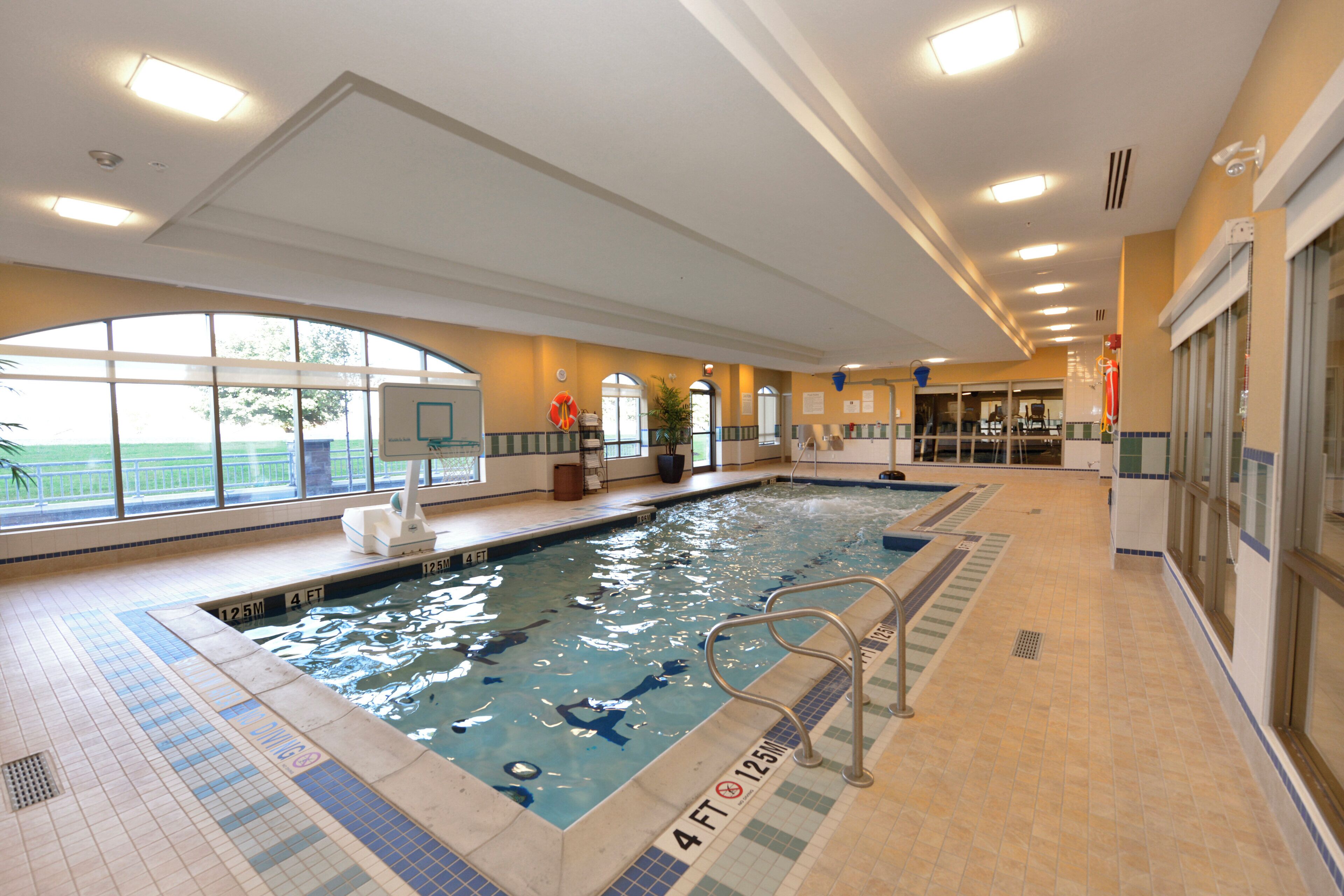 Ein Hallenbad mit klarem Wasser, einem Sprungturm und einem Rettungsschwimmerstuhl.