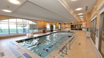 Ein Hallenbad mit klarem Wasser, einem Sprungturm und einem Rettungsschwimmerstuhl.
