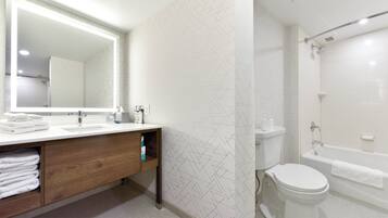 A modern bathroom with a vanity, sink, mirror, and a shower area.