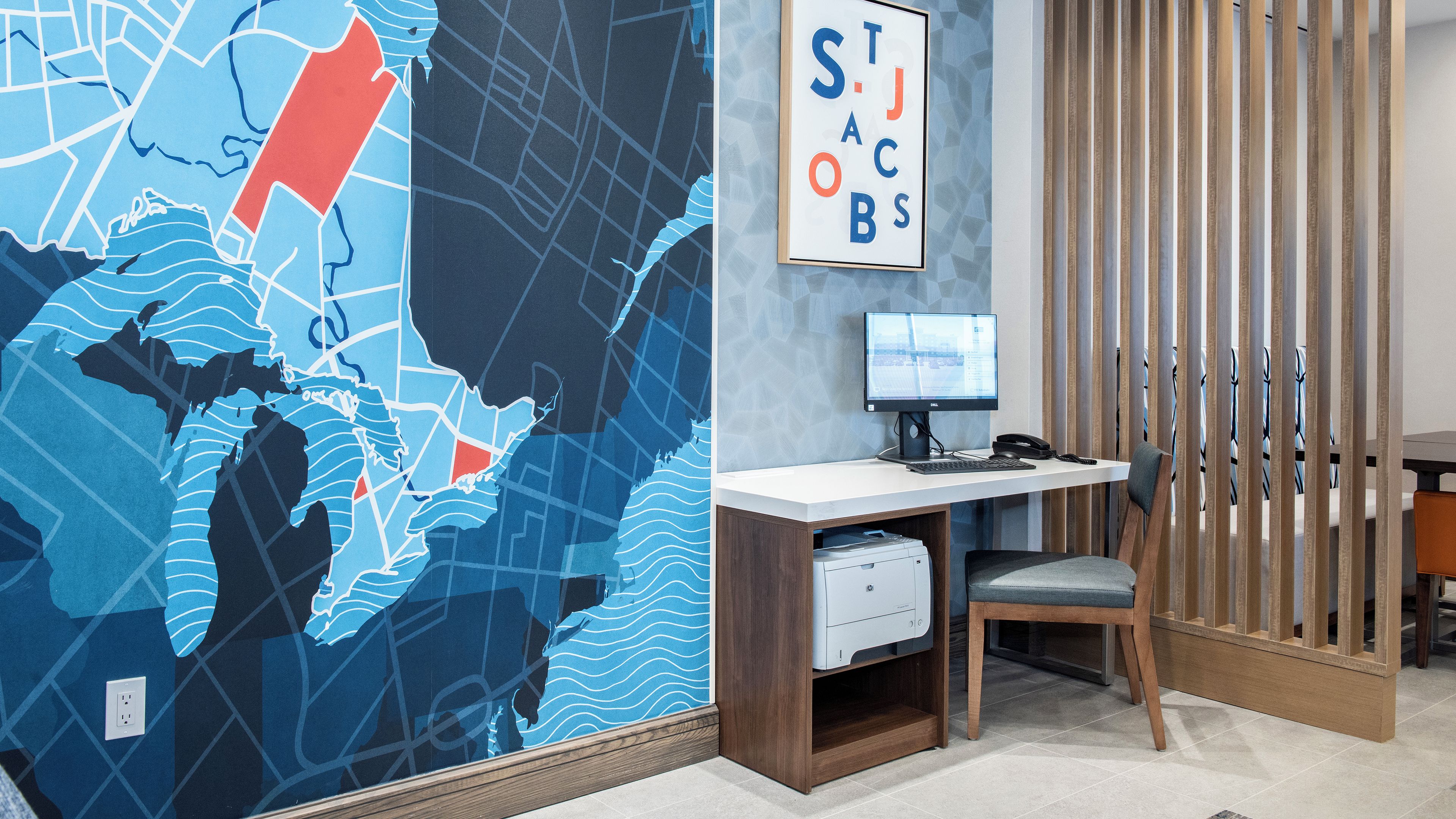 Un espace de bureau moderne comprenant une grande carte murale, un bureau avec un ordinateur et un téléphone.