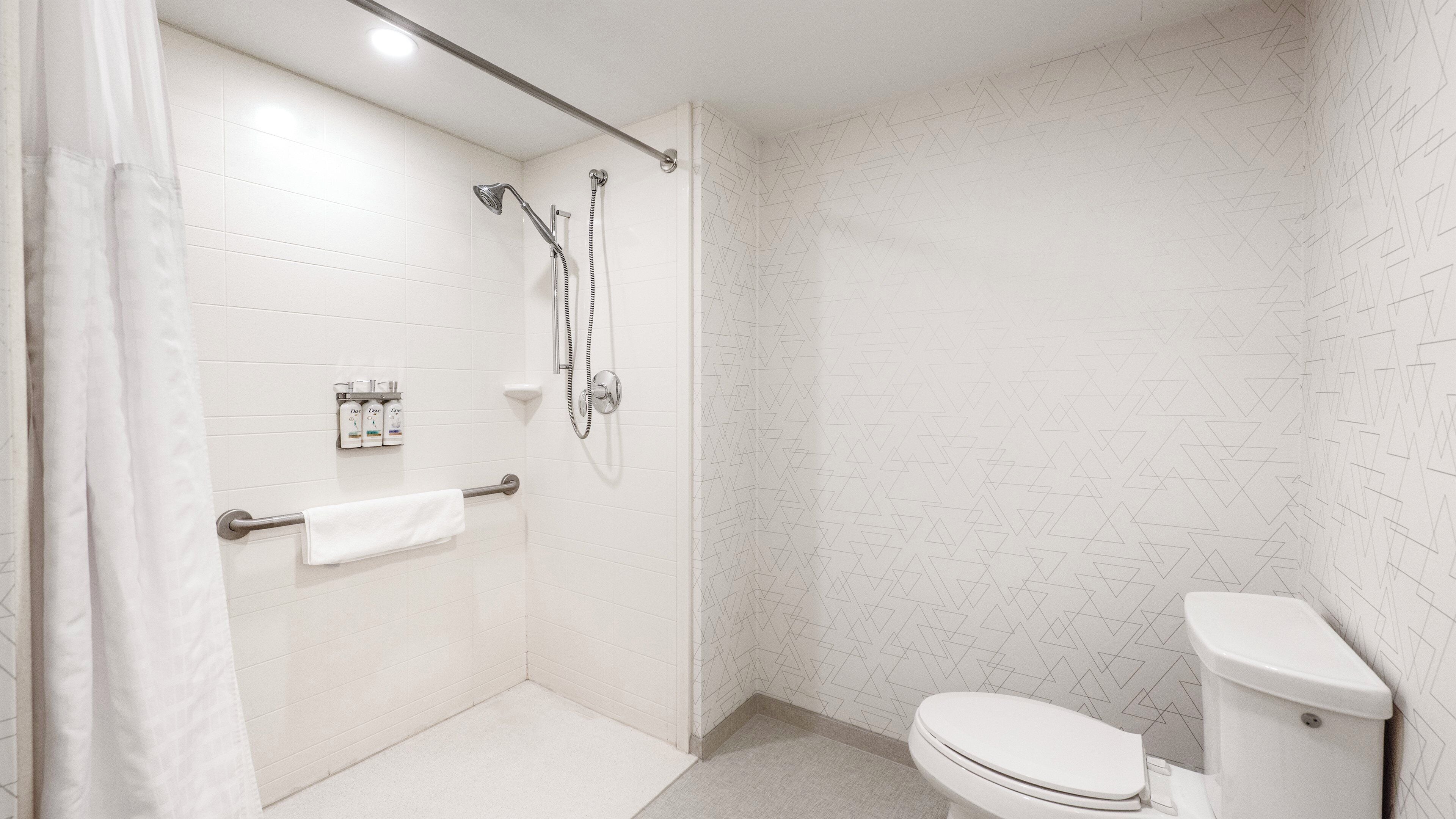 A modern bathroom with a shower, toilet, and towel rack.