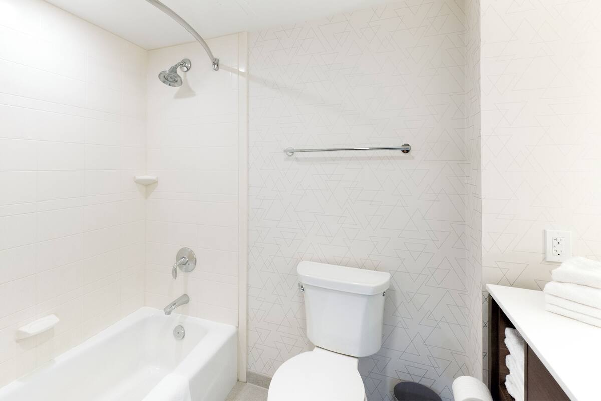 A modern bathroom with a bathtub, shower, toilet, and towel rack.