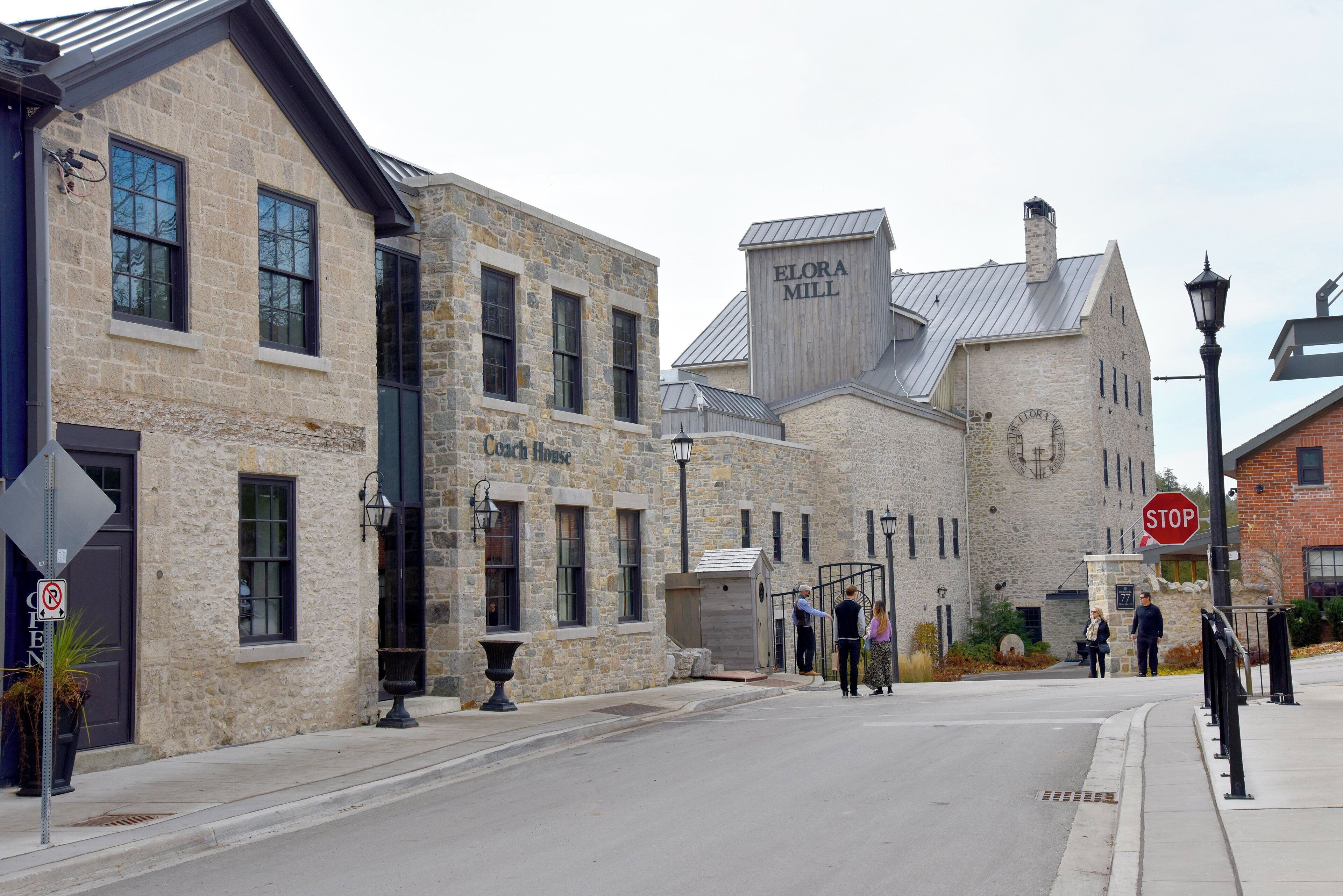 A historic stone building with a sign reading 'Coach House' and 'Elora Mill.'