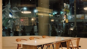 A modern dining area with a large rectangular table, wooden chairs, and a patterned rug. - V.L. HatYai Hotel (Hat Yai)