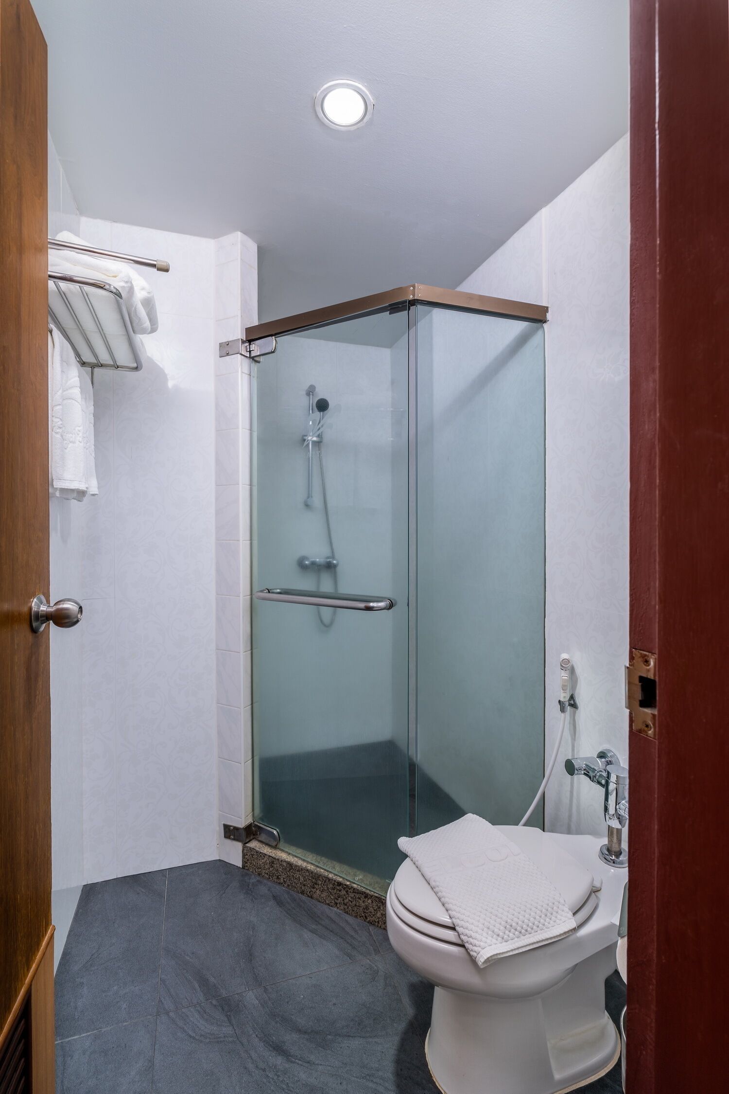 Ein Badezimmer mit einer Duschkabine, einer Toilette und einem Handtuchhalter.