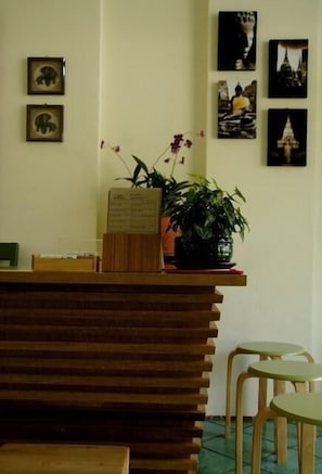 Una recepción con mostrador de madera, una planta en maceta y cuadros en la pared.