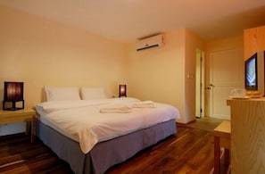 Una habitación de hotel con cama, mesita de noche y un pequeño escritorio con silla.