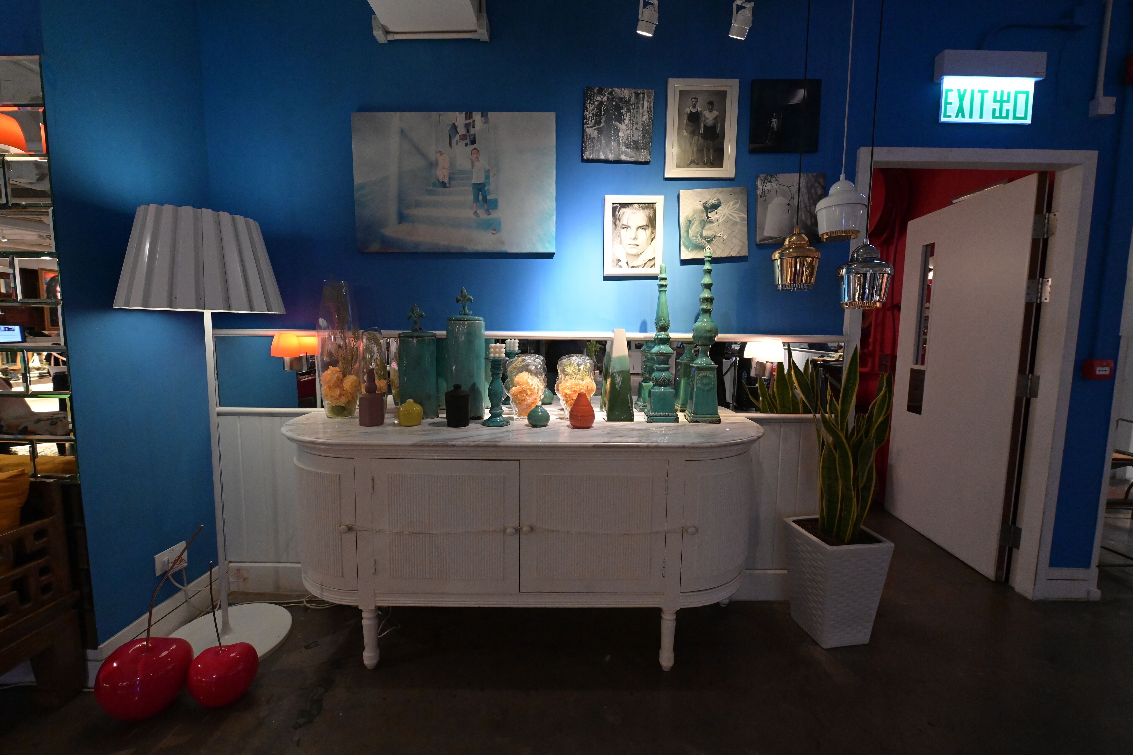 A room with a blue wall, white cabinets, and various decorative items on the counter.