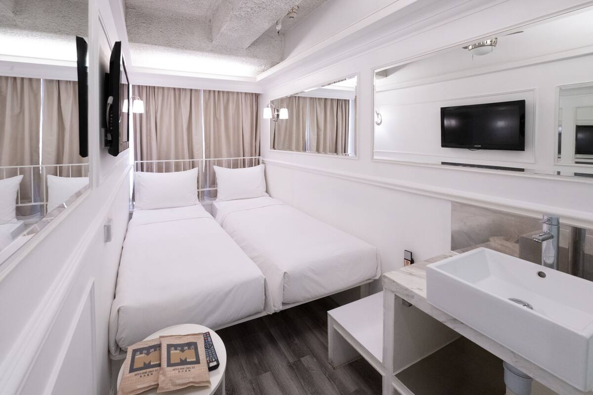 Hotelkamer met een groot bed, een aan de muur bevestigde televisie, een wastafel en een spiegel.