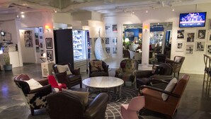 Een moderne lounge met lederen en gestreepte fauteuils, een ronde centrale tafel en een televisie aan de muur.