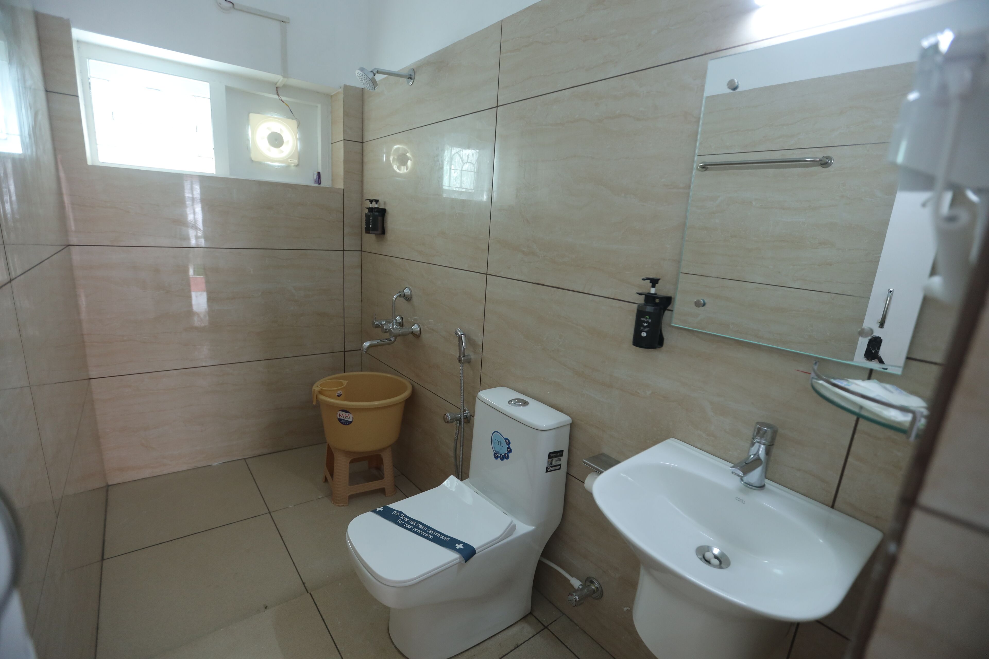 Ein Badezimmer mit Toilette, Waschbecken und einem kleinen Hocker.
