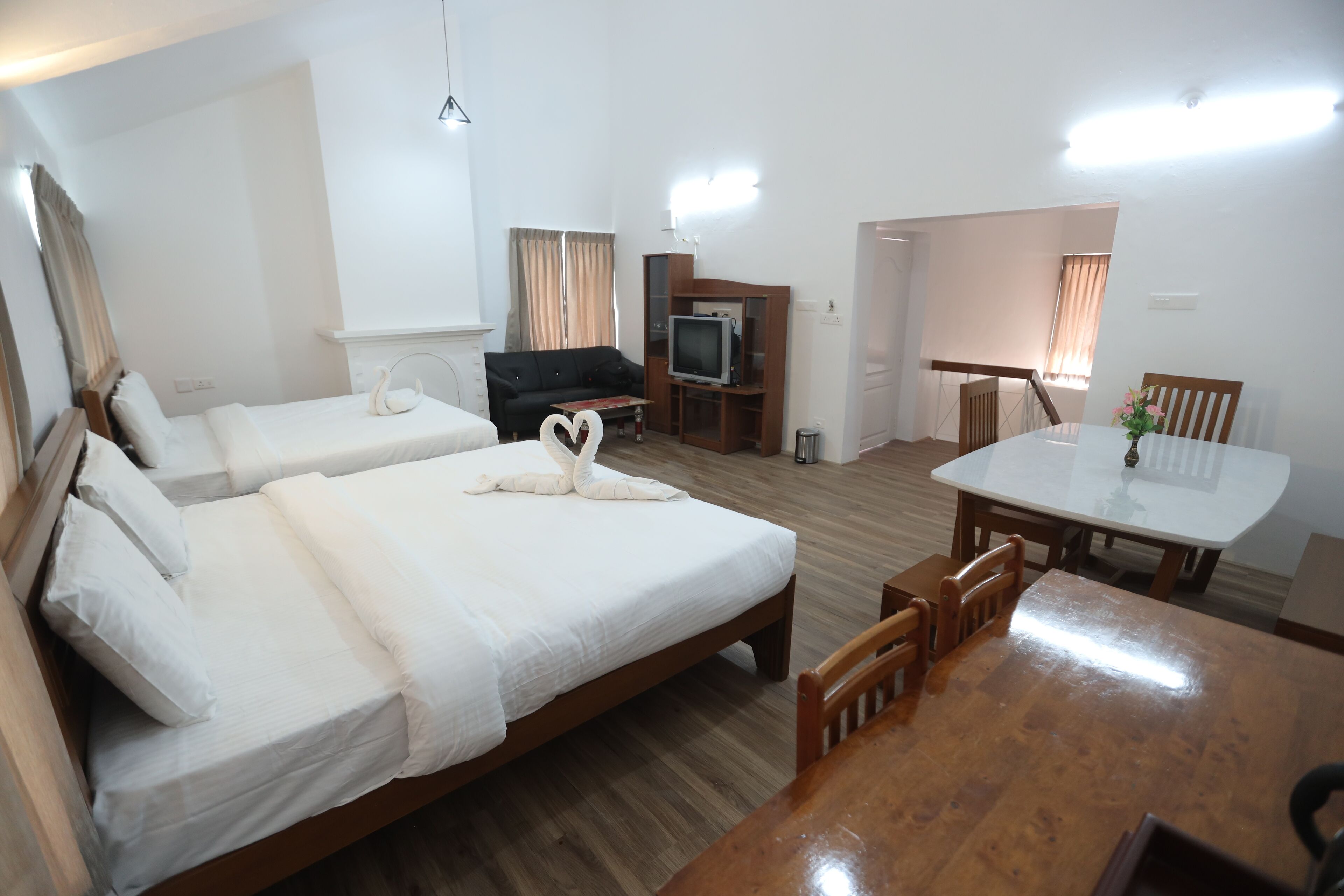 Habitación de hotel con dos camas, una mesa de comedor, televisión y una escalera.