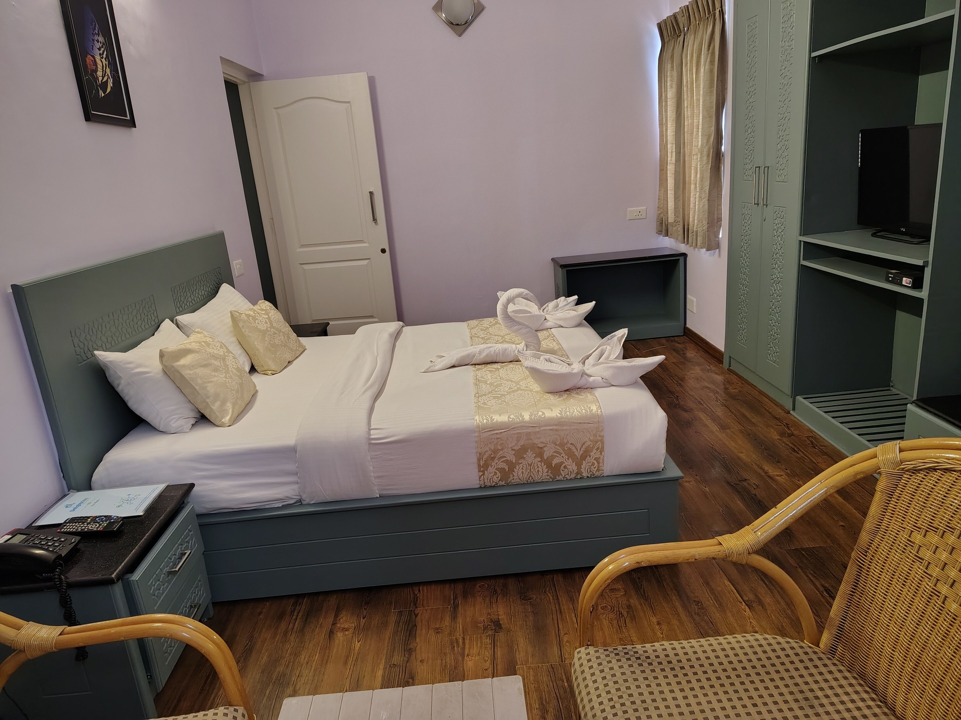 A neatly made bed with towels, a bedside phone, and a small table with a book.