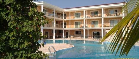 Un hotel con piscina, varios balcones y una estructura de dos pisos.