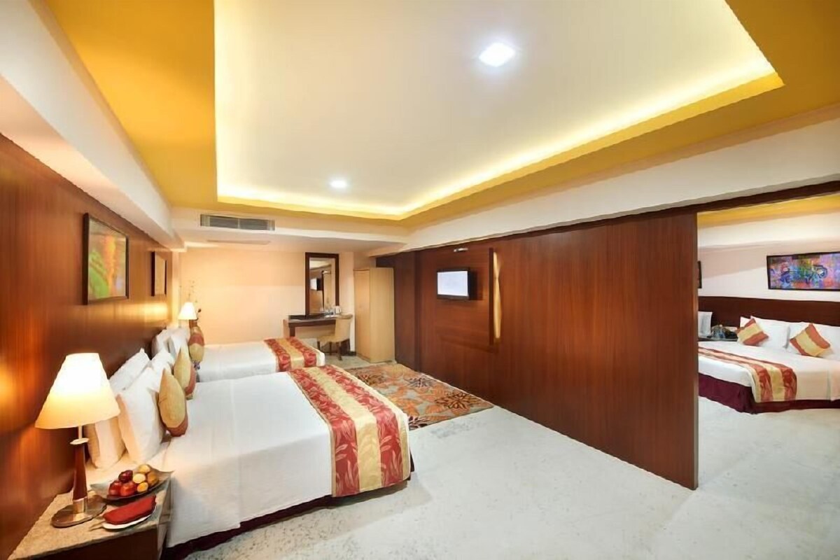 A hotel room with two beds, a desk, a TV, and a large mirror.