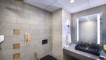 A modern bathroom with a large mirror, a black sink, and multiple showerheads.