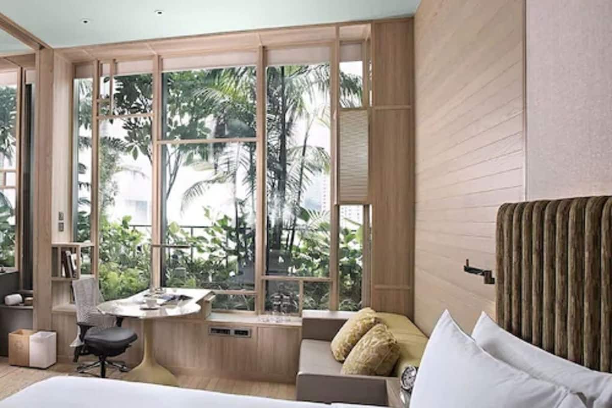 Une chambre d’hôtel moderne dotée d’un grand lit, d’un bureau et offrant une vue sur une végétation tropicale luxuriante.