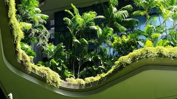 Un atrio de varios niveles con abundante vegetación y arquitectura moderna.