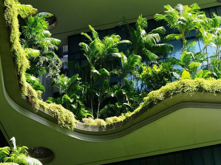 Un atrio de varios niveles con abundante vegetación y arquitectura moderna.