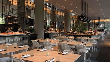 Un restaurante moderno con una barra larga, varias mesas y una zona de bar.