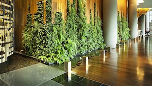 A modern lobby with vertical gardens, wooden paneling, and a polished floor.