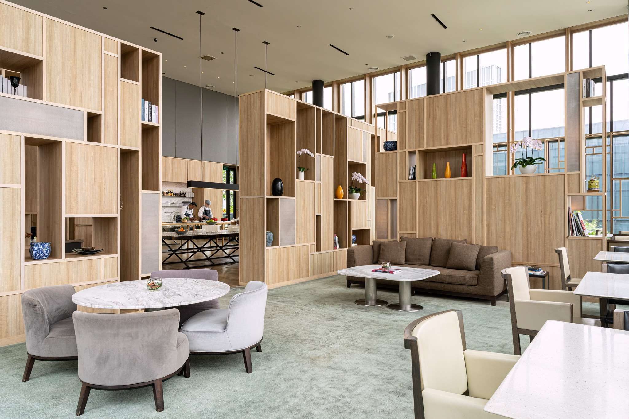 A spacious library with wooden bookshelves, comfortable seating, and large windows.