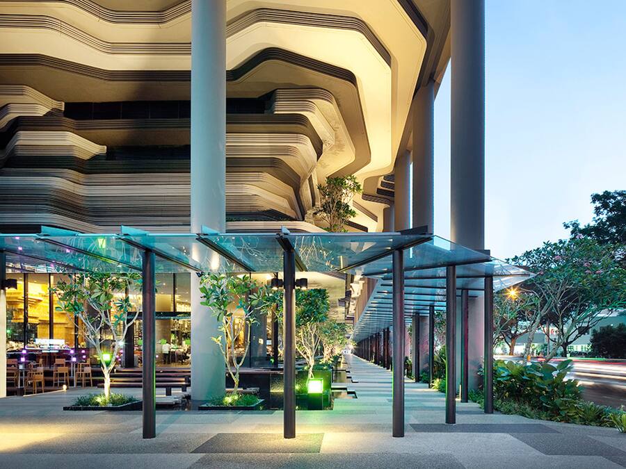 A modern building with a unique architectural design featuring curved lines and a glass canopy over an outdoor seating area.