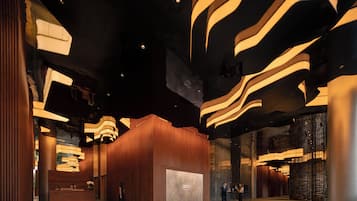A spacious lobby with a modern design, featuring a reception desk, a large wall with a display, and a seating area.