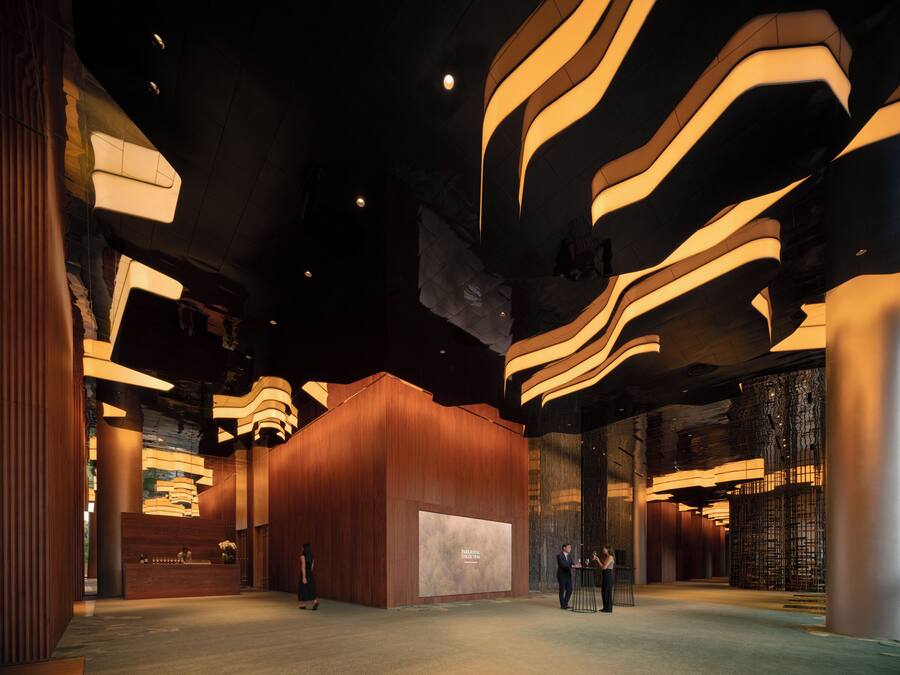 A spacious lobby with a modern design, featuring a reception desk, a large wall with a display, and a seating area.