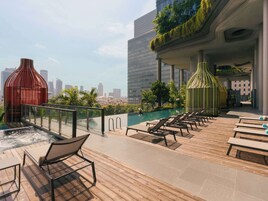 A rooftop pool area with lounge chairs and a view of the city skyline.