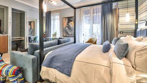 Una habitación de hotel moderna con una cama grande, un sofá, un escritorio y vistas a la ciudad.