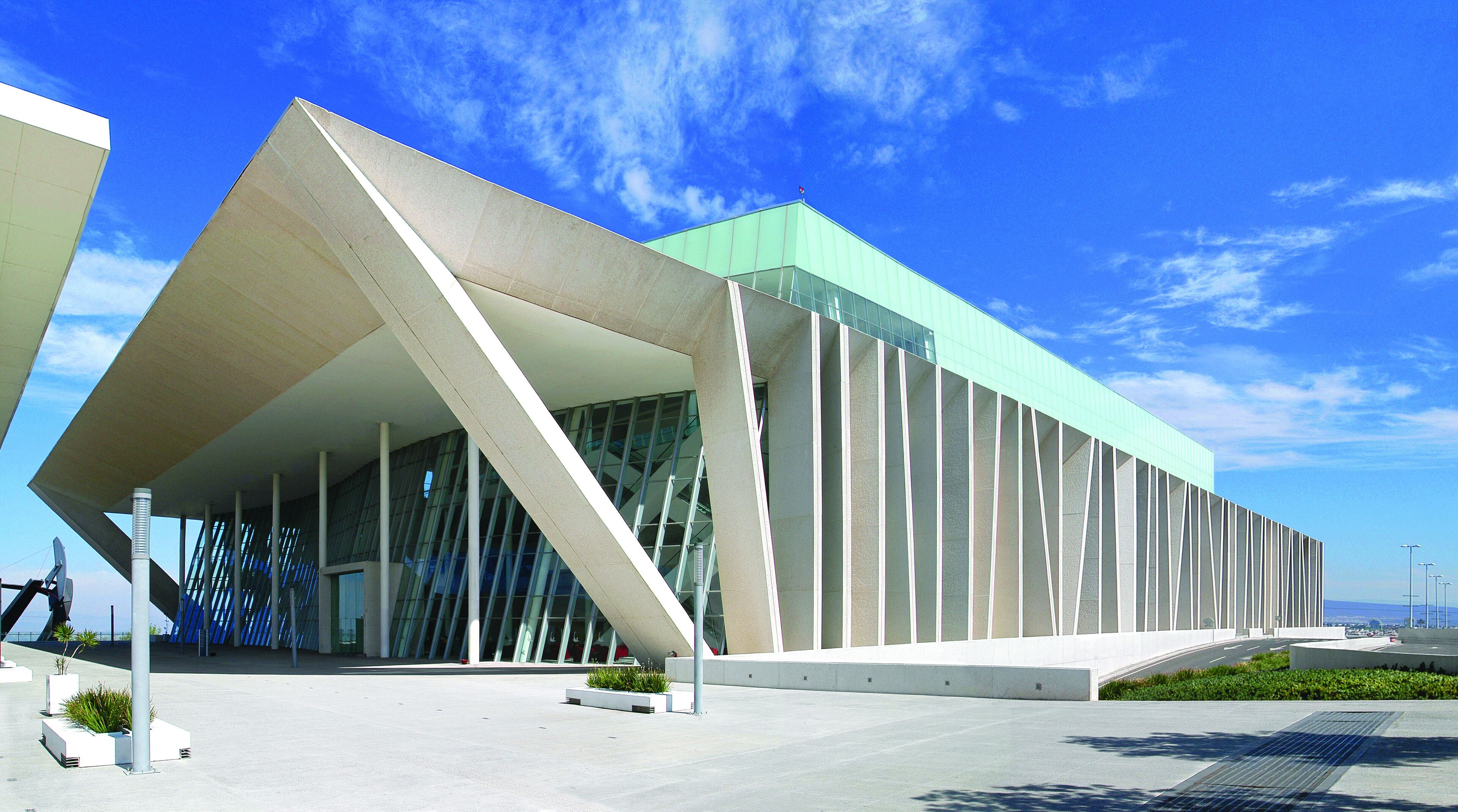 Un edificio moderno con un diseño angular distintivo, grandes ventanales y techo plano.