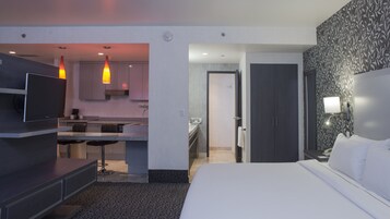 Habitación de hotel moderna con cama, televisión, kitchenette y baño.
