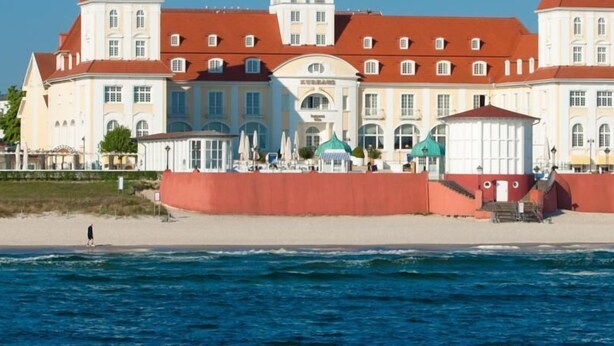 Ein großes, mehrstöckiges Gebäude mit rotem Dach und weißen Wänden in Strandnähe.