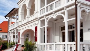 Ein weißes Gebäude mit Balkon, Treppe und Außenbereich mit Sitzgelegenheiten.