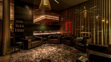 A modern lounge area with leather seating, a fireplace, and a bookshelf.