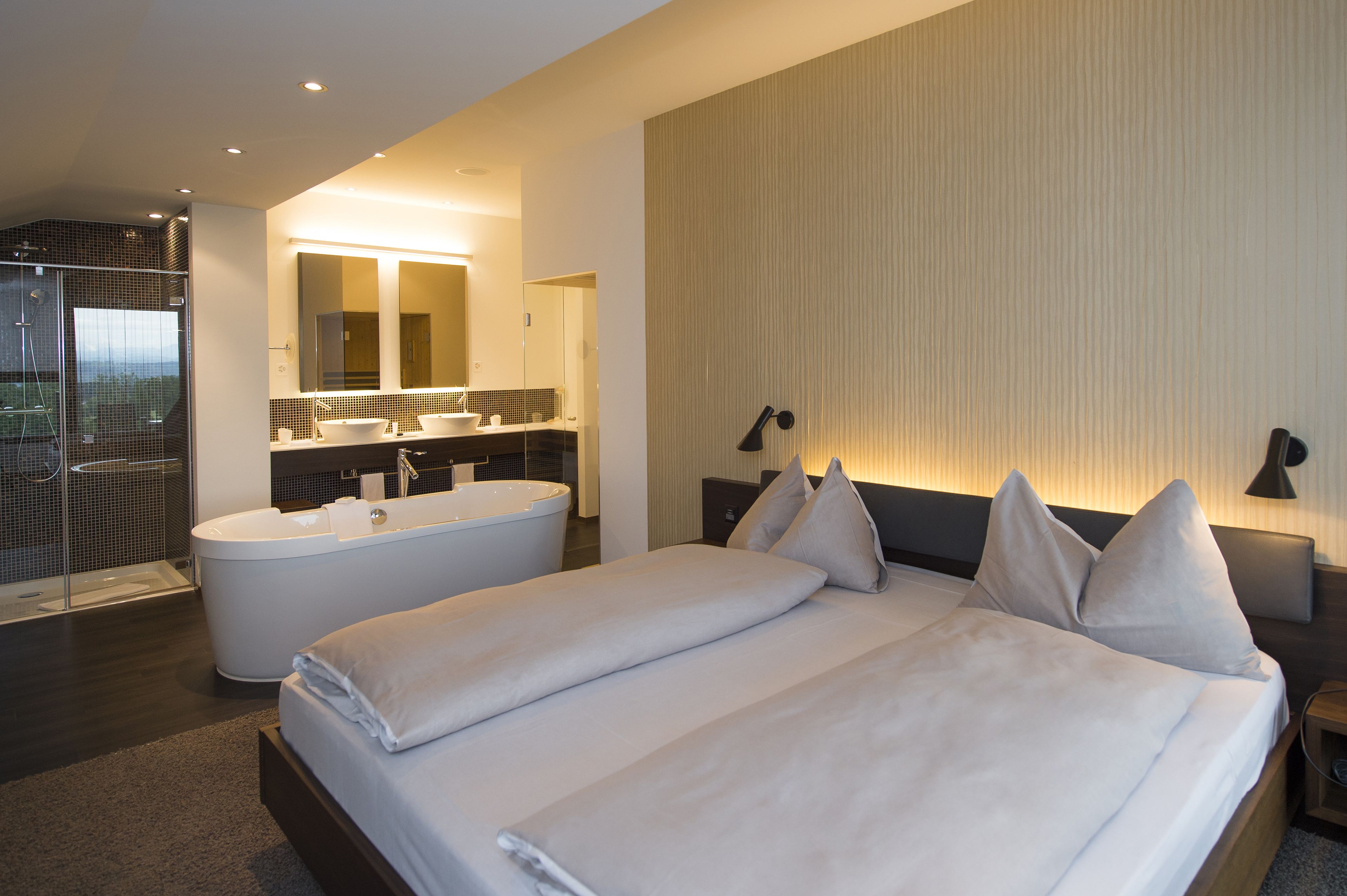 Ein modernes Hotelzimmer mit einem großen Bett, einem separaten Badezimmer mit einer Badewanne und einer Duschkabine.